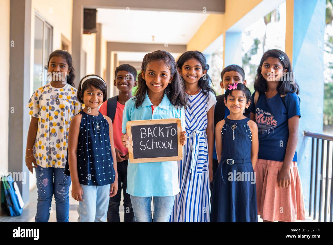Girl kid holding back to school sign board in front of school children ...
