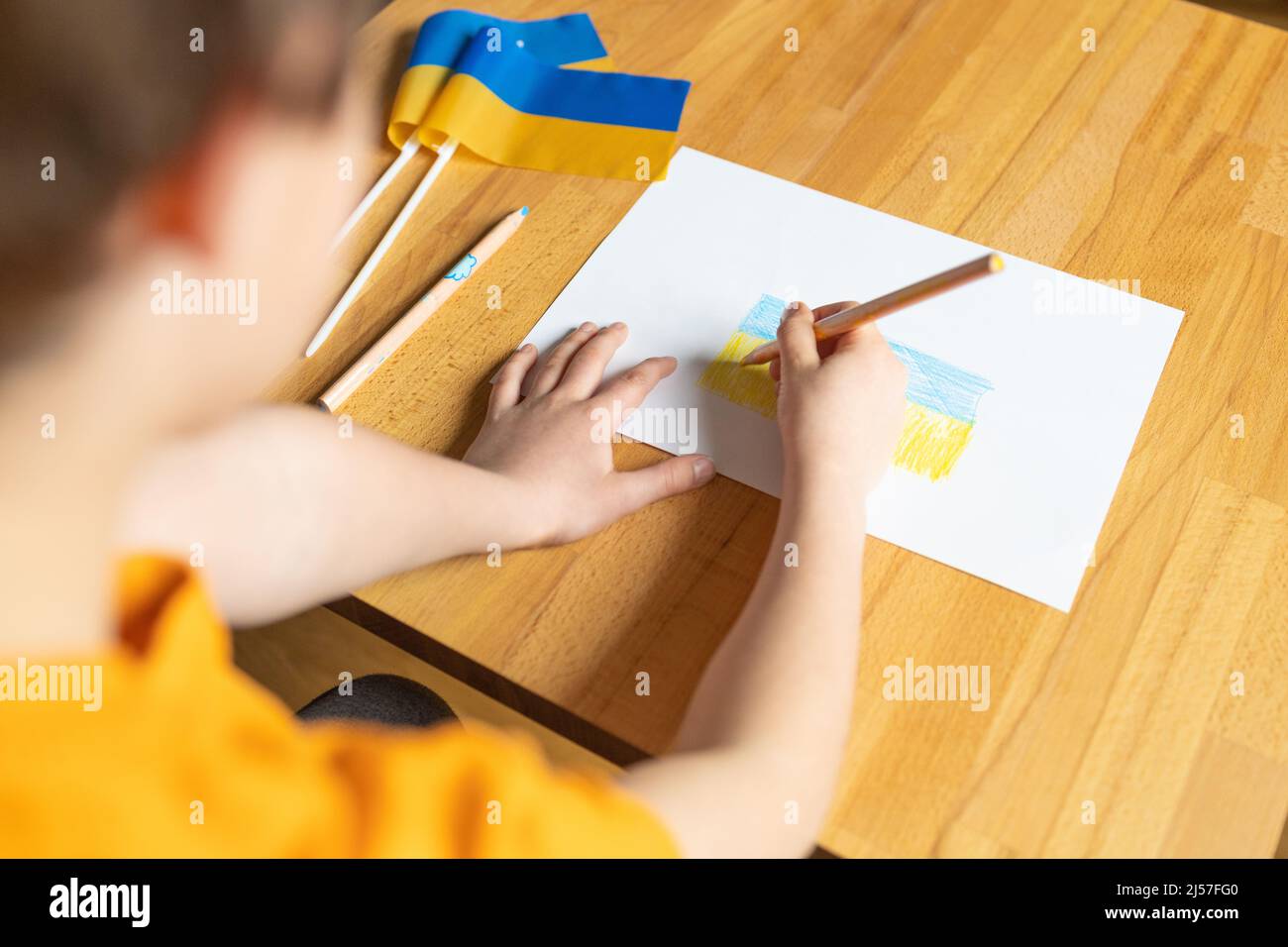 Children hands with yellow and blue color pencil drawing 