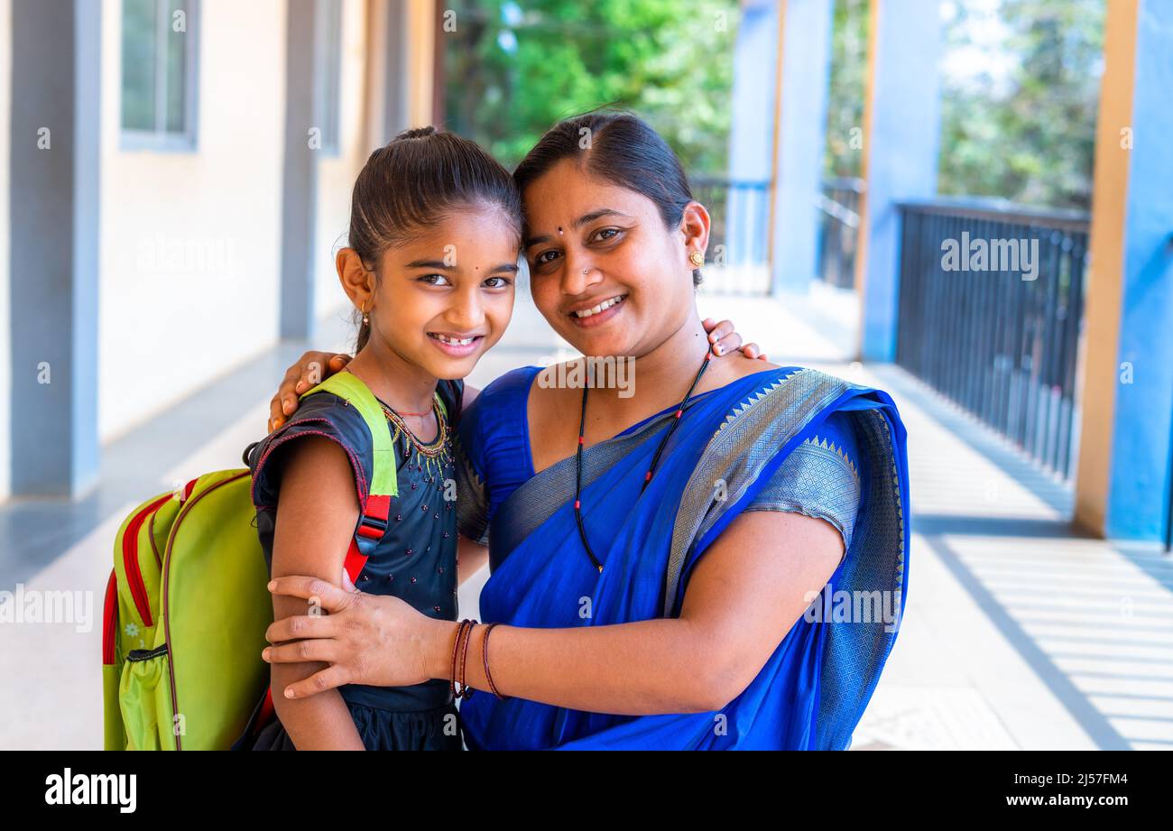 happy smiling Mother embracing her daughter before going to classrrom at school corridor by looking at camera - concept of back to school Stock Photo