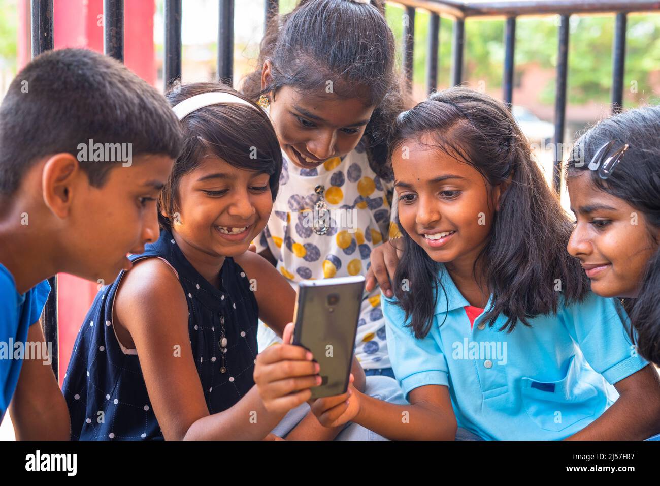 Kids at school busy using mobile phone while sitting at corridor during