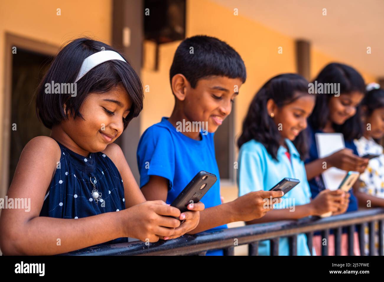 Group of kids busy using mobile phone at school corridor - concept of socil media, smartphone technology and gaming addiction Stock Photo
