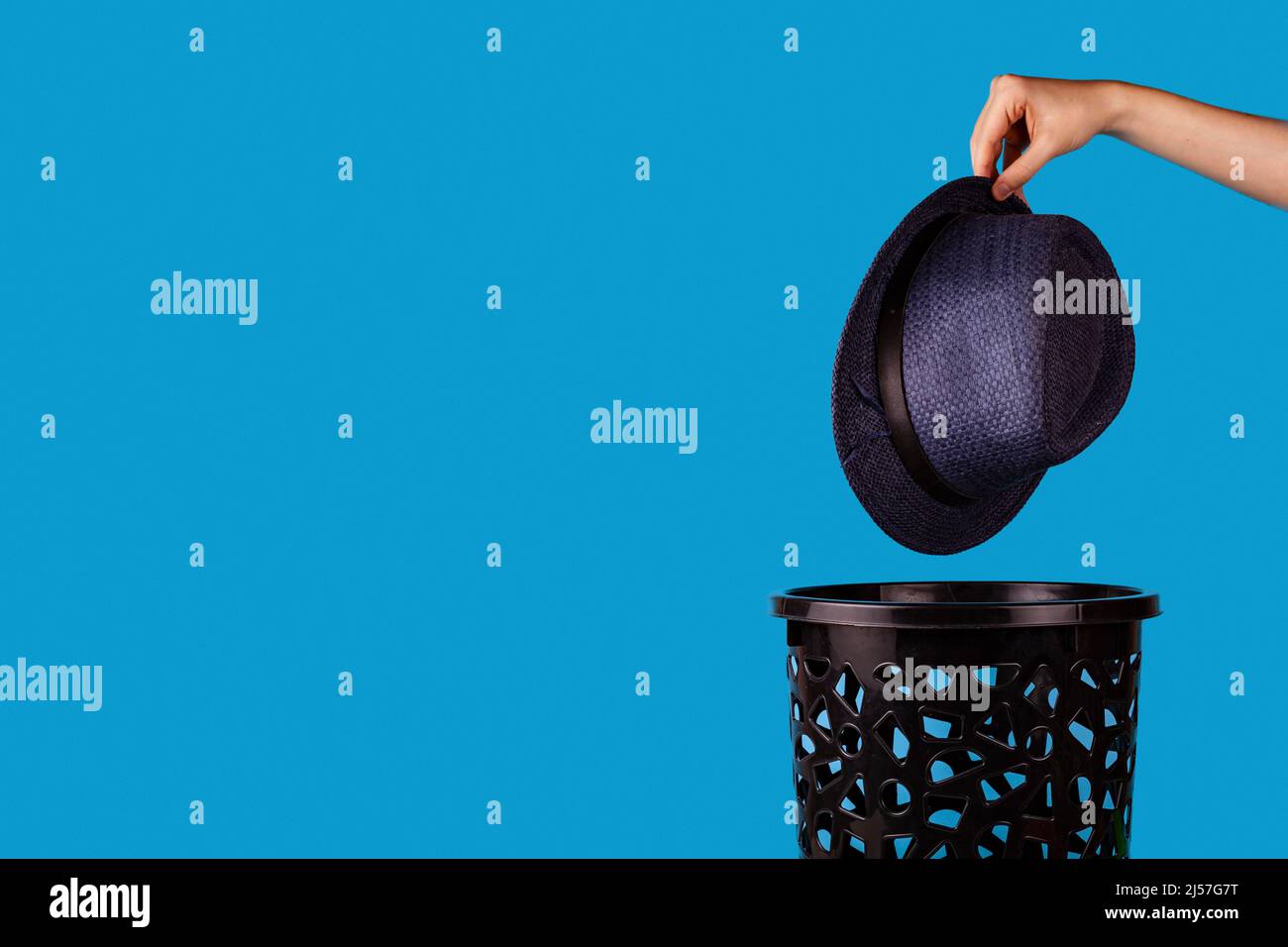 Hat are thrown in the trash can. For copy space for designers on a blue background. Stock Photo