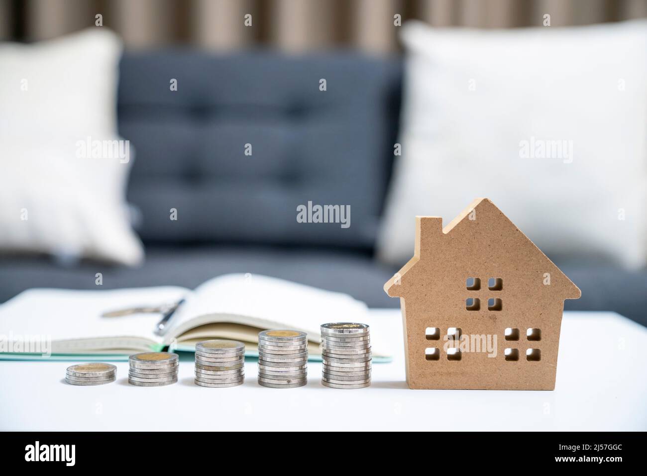 Stack money coin and a mini house on the table, saving money concept. Stock Photo