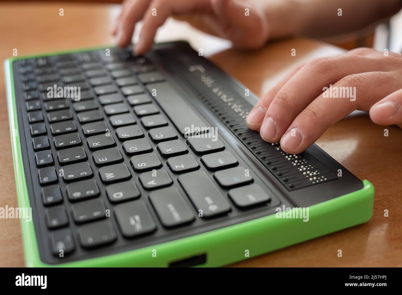 A blind man uses a computer with a Braille display and a computer