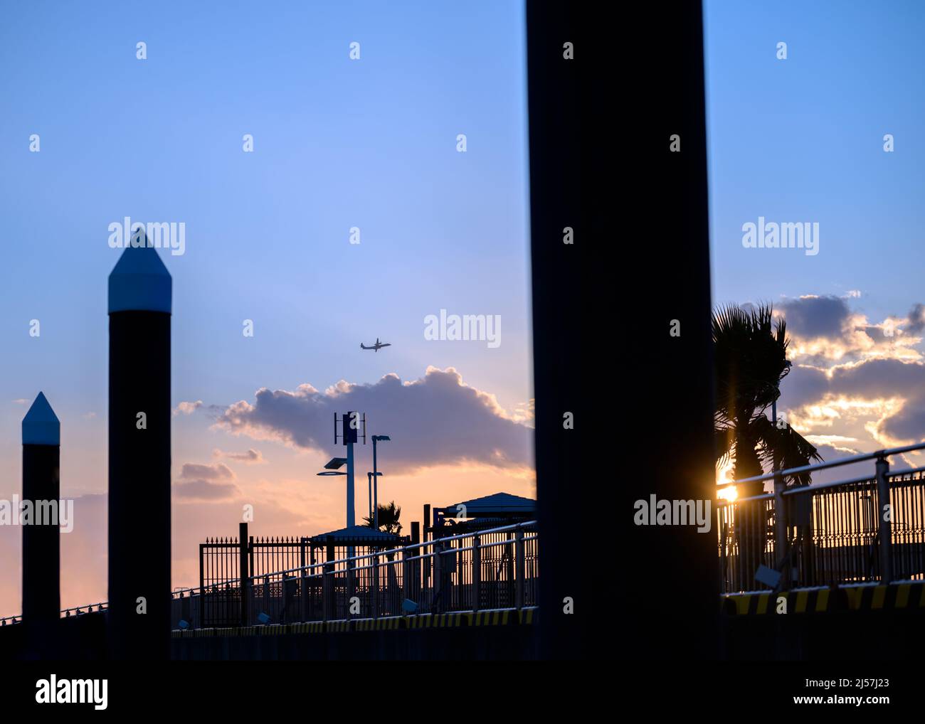 Sunset at a harbor with an airplane in the sky. Blue hour. Stock Photo