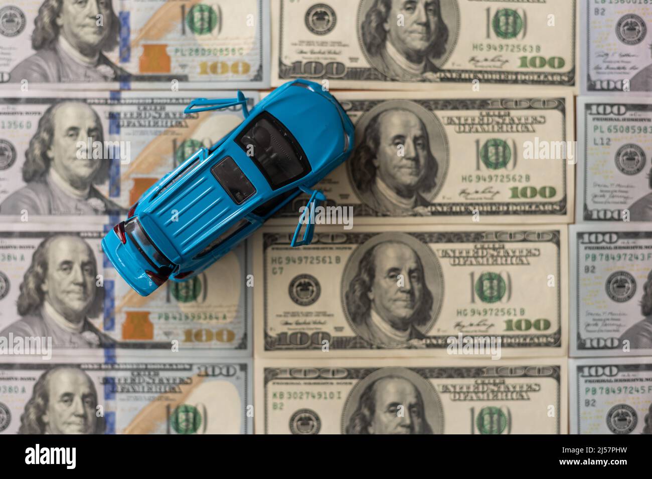 Small toy car on one hundred dollar banknotes as road, isolated on ...