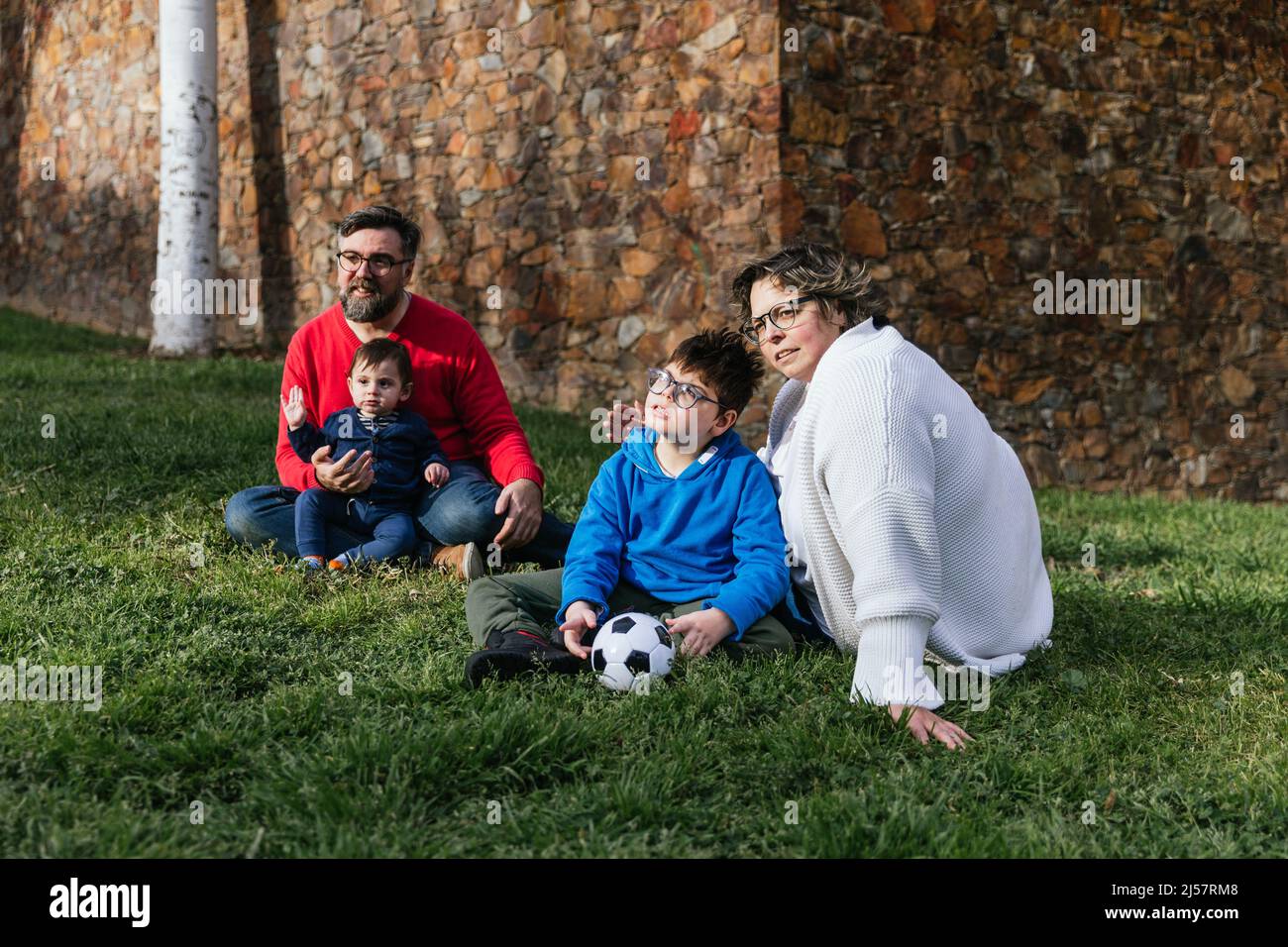 A happy family enjoying a day in the park together sitting on the grass ...