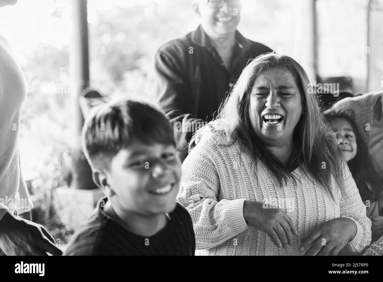 Happy latin family having fun together at home - Soft focus grandmother face - Black and white editing Stock Photo