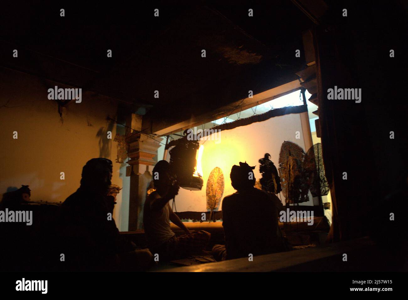 Puppet master and his assistants behind the screen after shadow puppet