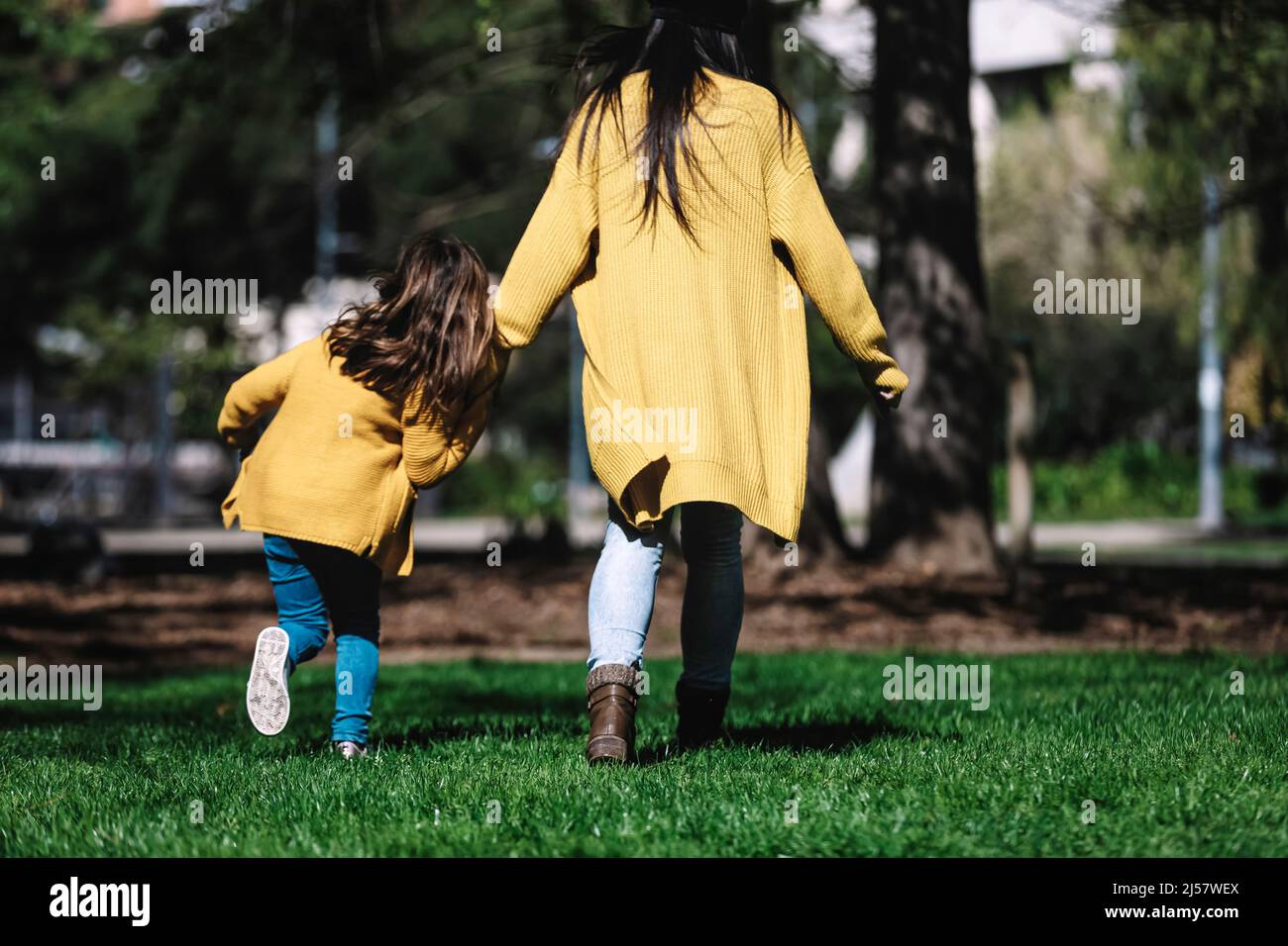Rear view of a mother with her baby. Mom and daughter in an autumn park ...