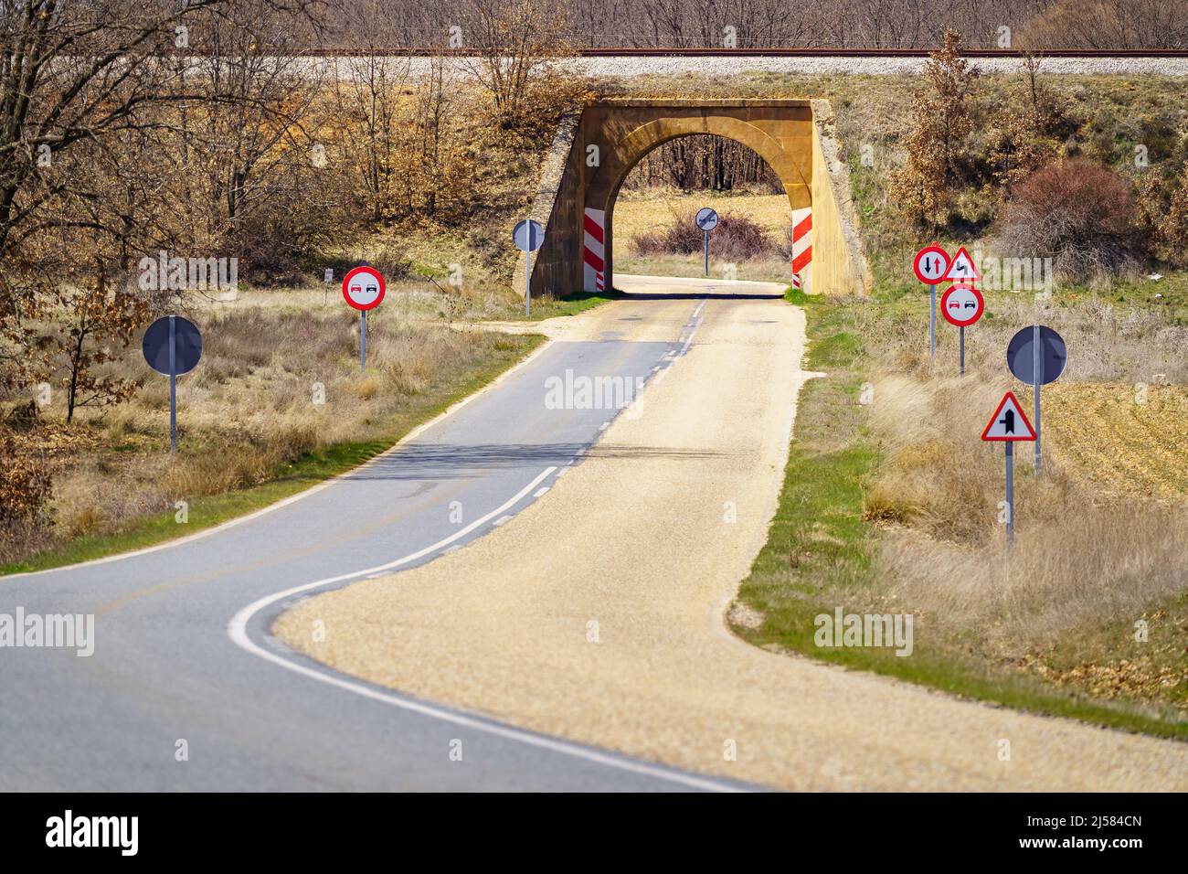 Secondary mountain road full of traffic signs and tunnel under the train track. Stock Photo