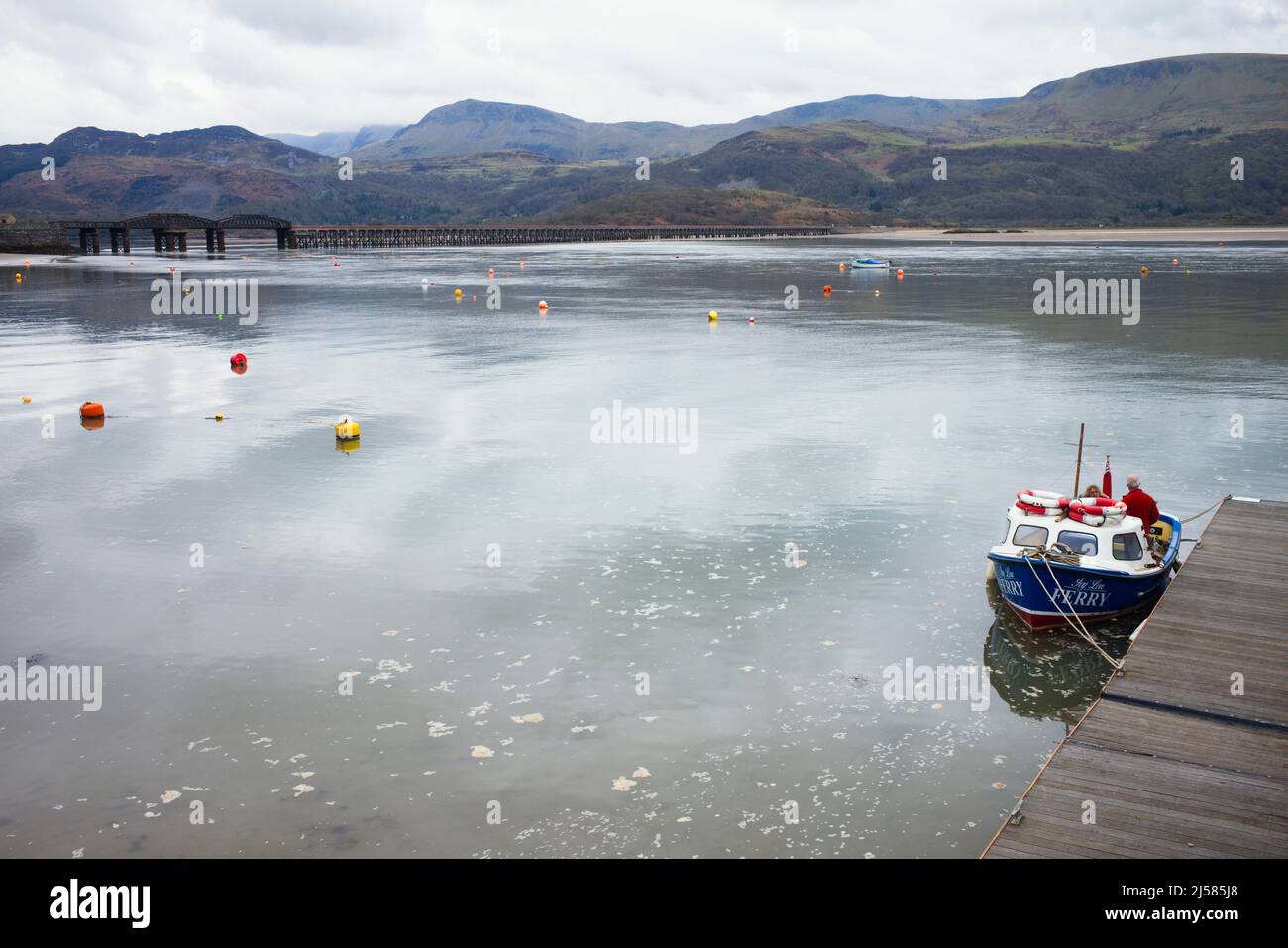Ferry boat moored at Barmouth harbour with railway bridge in background Stock Photo