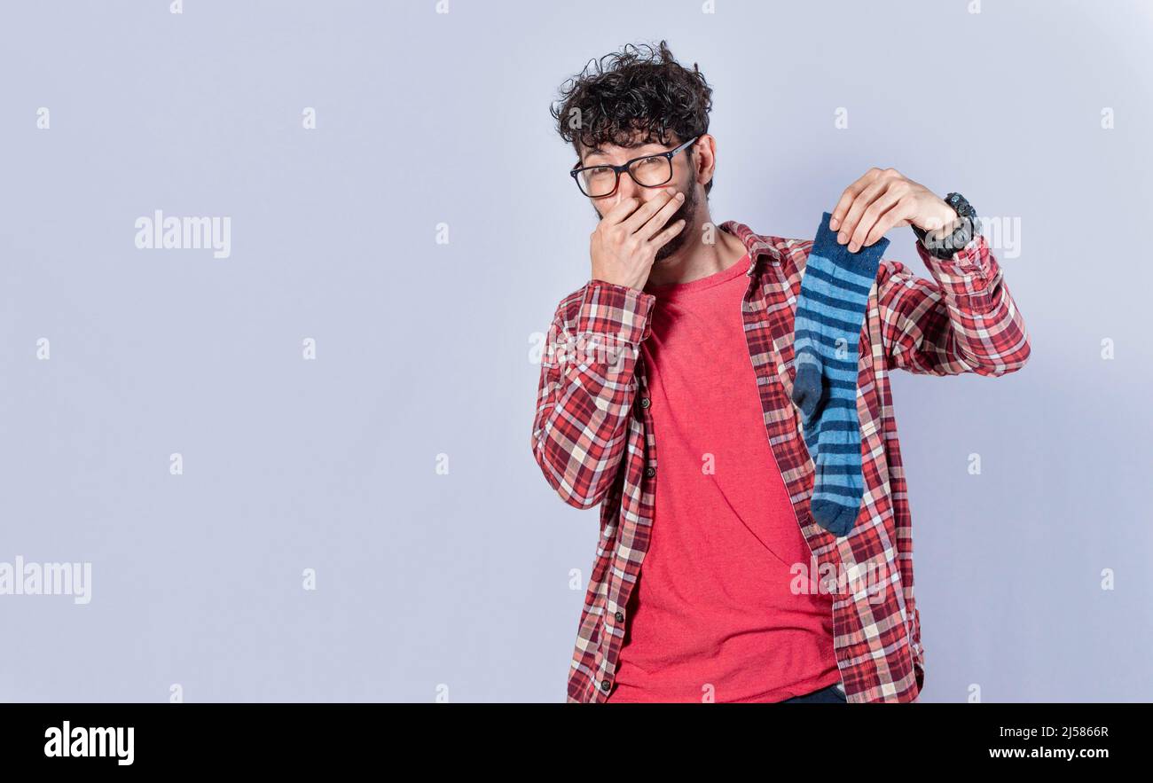 A man with a sock in his hand covering his nose, a guy with a stinky sock in his hand, smelly socks concept Stock Photo