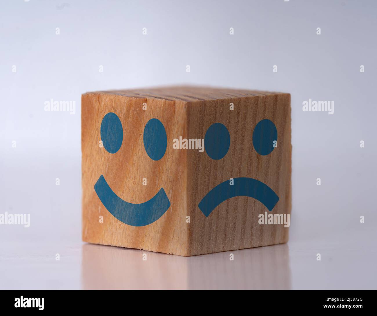 Photo of a wooden cube with happy and sad face expressions as a symbol of instat personality shifts. Concept of bipolar , unipolar and borderline. Stock Photo