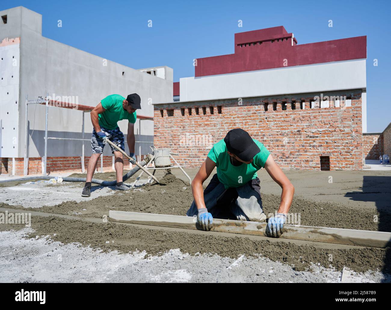 Contractors placing screed rail on the floor covered with sand-cement ...