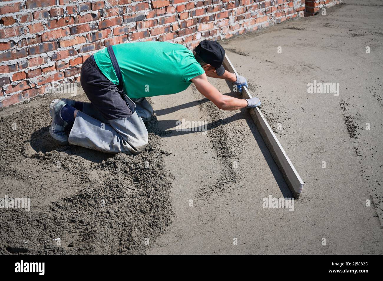 Man builder placing screed rail on the floor covered with sandcement