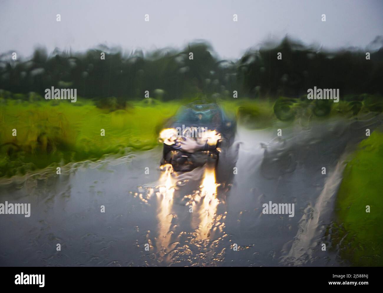 Blick durch eine nasse Windschutzscheibe auf ein fahrendes Auto auf einer Strasse bei Regenwetter, Strassenverkehr, Oberoesterreich, Oesterreich Stock Photo