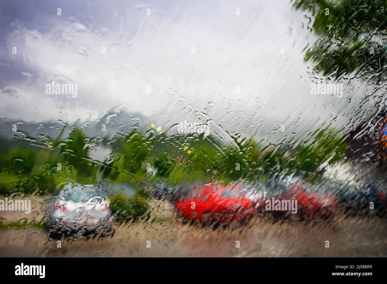 Blick durch eine nasse Windschutzscheibe auf geparkte Autos am Parkplatz, Oberoesterreich, Oesterreich Stock Photo