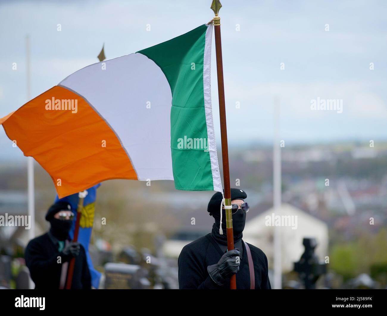 Masked man in paramilitary uniform carries Irish tricolour flag at an Easter Monday Dissident Republican parade in Derry, Northern Ireland 18 March 2022. ©George Sweeney / Alamy Stock Photo Stock Photo