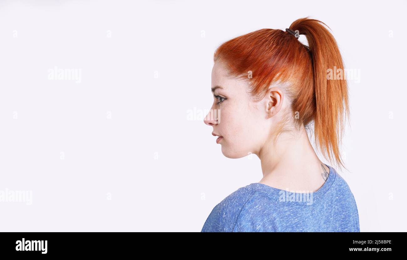 young woman with dyed red hair tied back in a ponytail with scrunchie Stock Photo