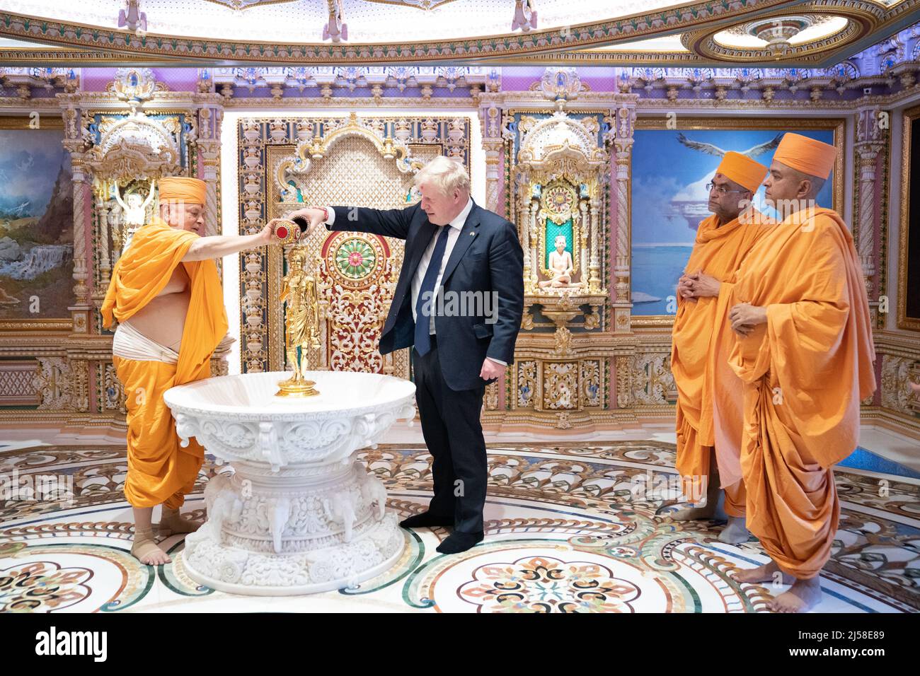 Prime Minister Boris Johnson is watched by sadhus, Hindu holymen, as he pours water on statue in the Abhishek at the Swaminarayan Akshardham temple in Gandhinagar, Ahmedabad, as part of his two day trip to India. Picture date: Thursday April 21, 2022. Stock Photo