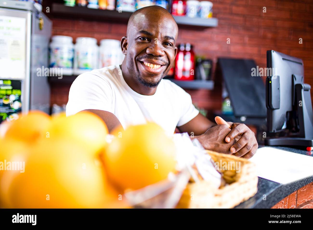hispanic man selling professional plastic jar with sport nutrition in reception of gym Stock Photo