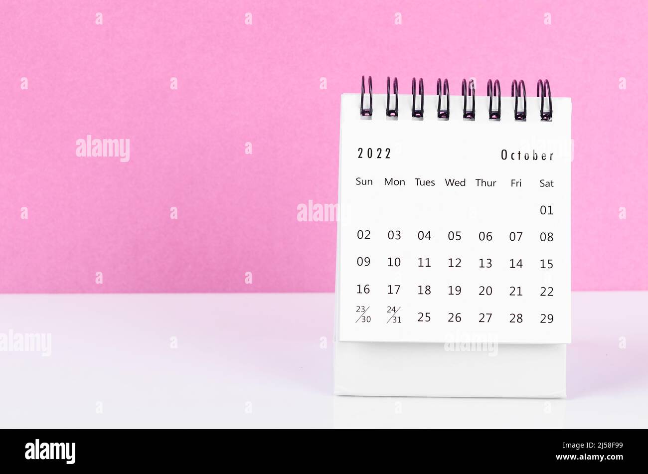 The October 2022 desk calendar on white table with pink background. Stock Photo