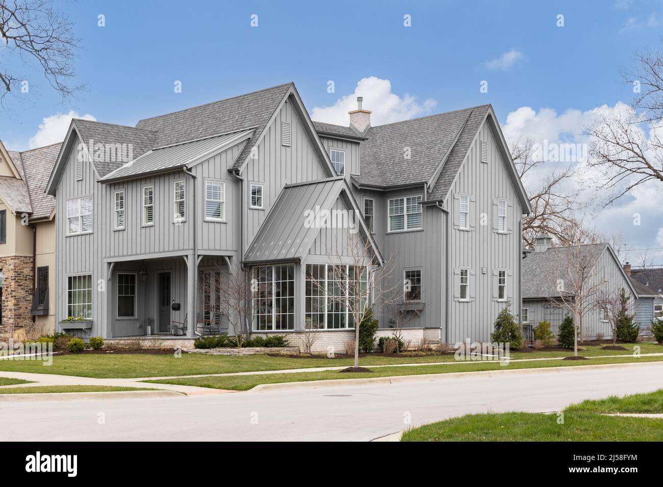 A large grey modern farmhouse with a covered front porch, large windows