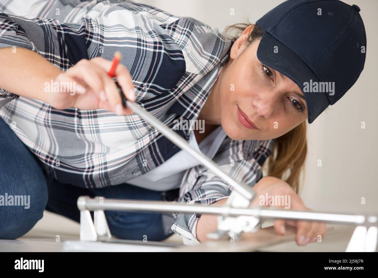 female worker is assembling metal-plastic window in workshop Stock Photo
