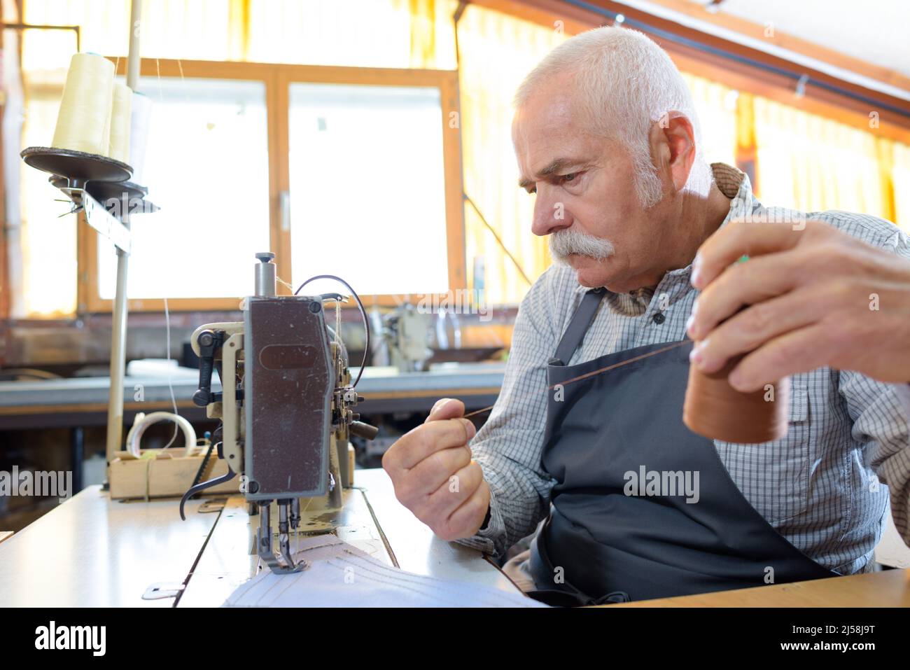 senior man using industrial sewing machine Stock Photo