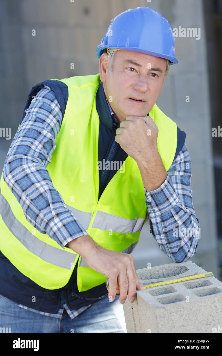 builder measures aerated concrete block with measuring tape Stock Photo