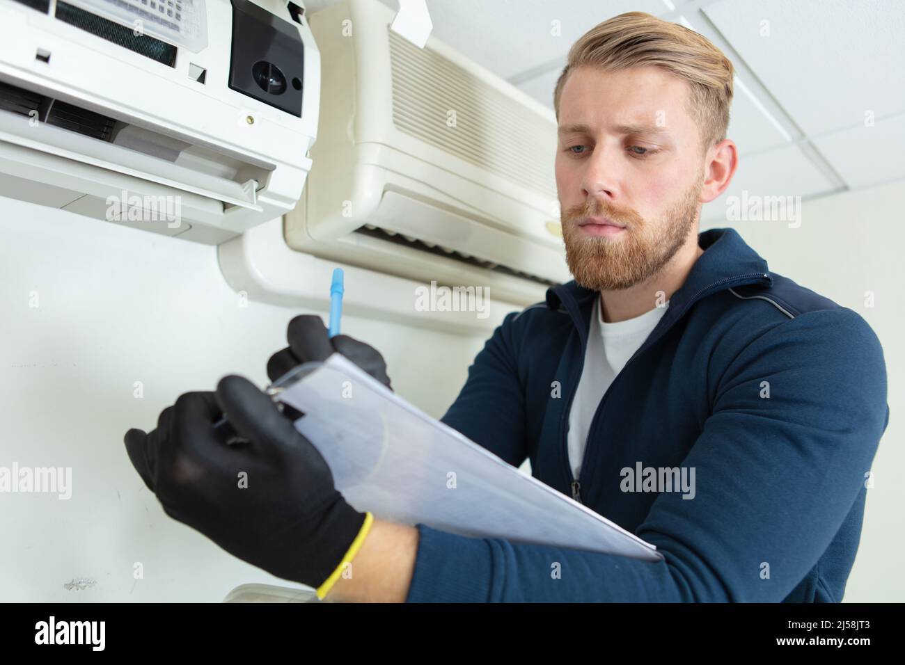 young male technician checking air conditioning system Stock Photo