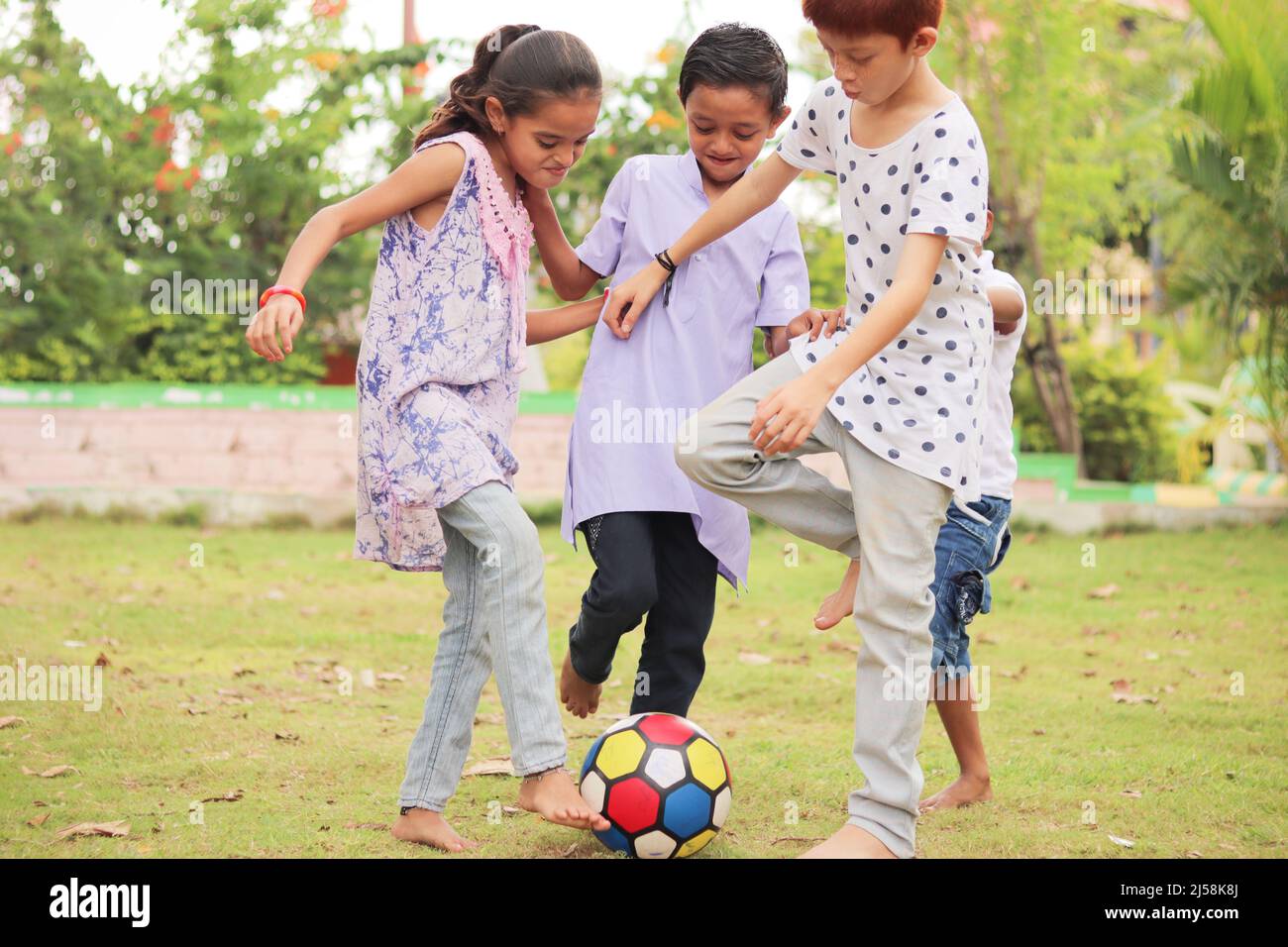 group of multiethnic diverse kids playing football at park - concept of summer vacation, holidays, active childhood lifestyle Stock Photo