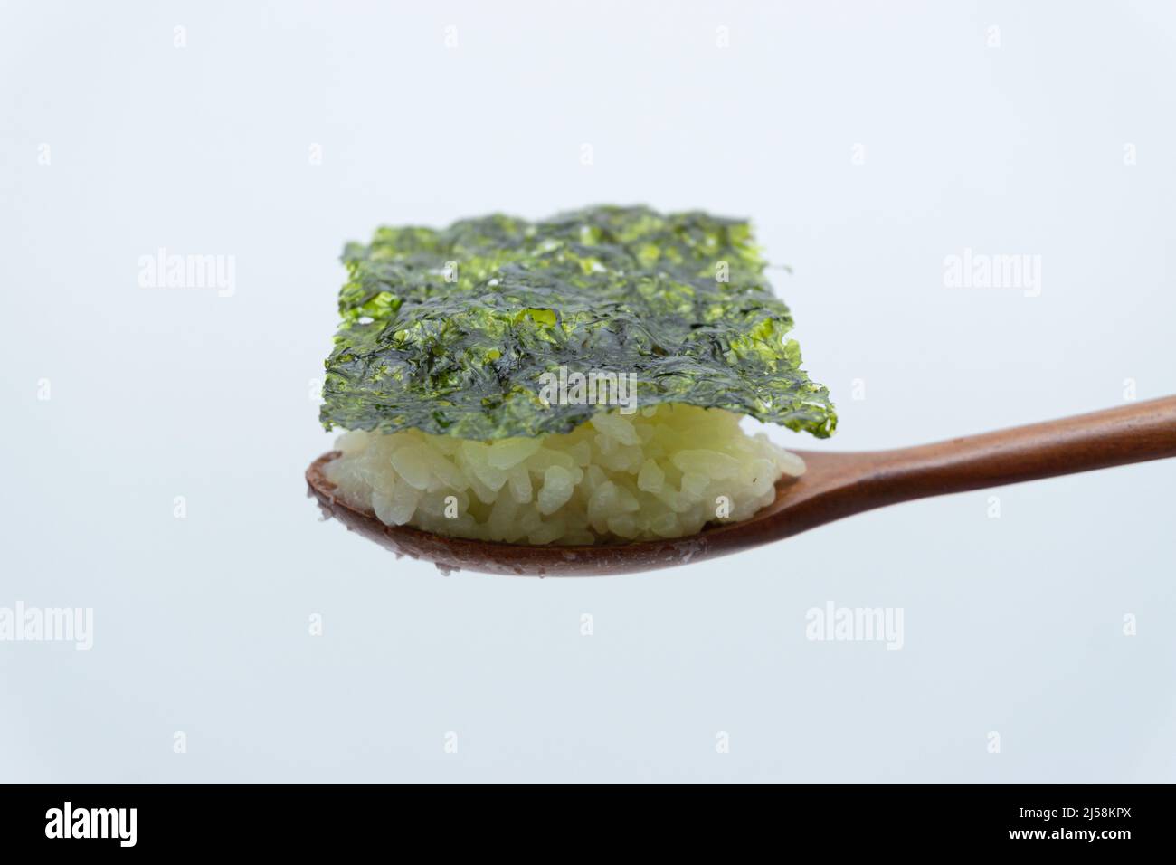 White rice and seaweed on a spoon on a white background Stock Photo - Alamy
