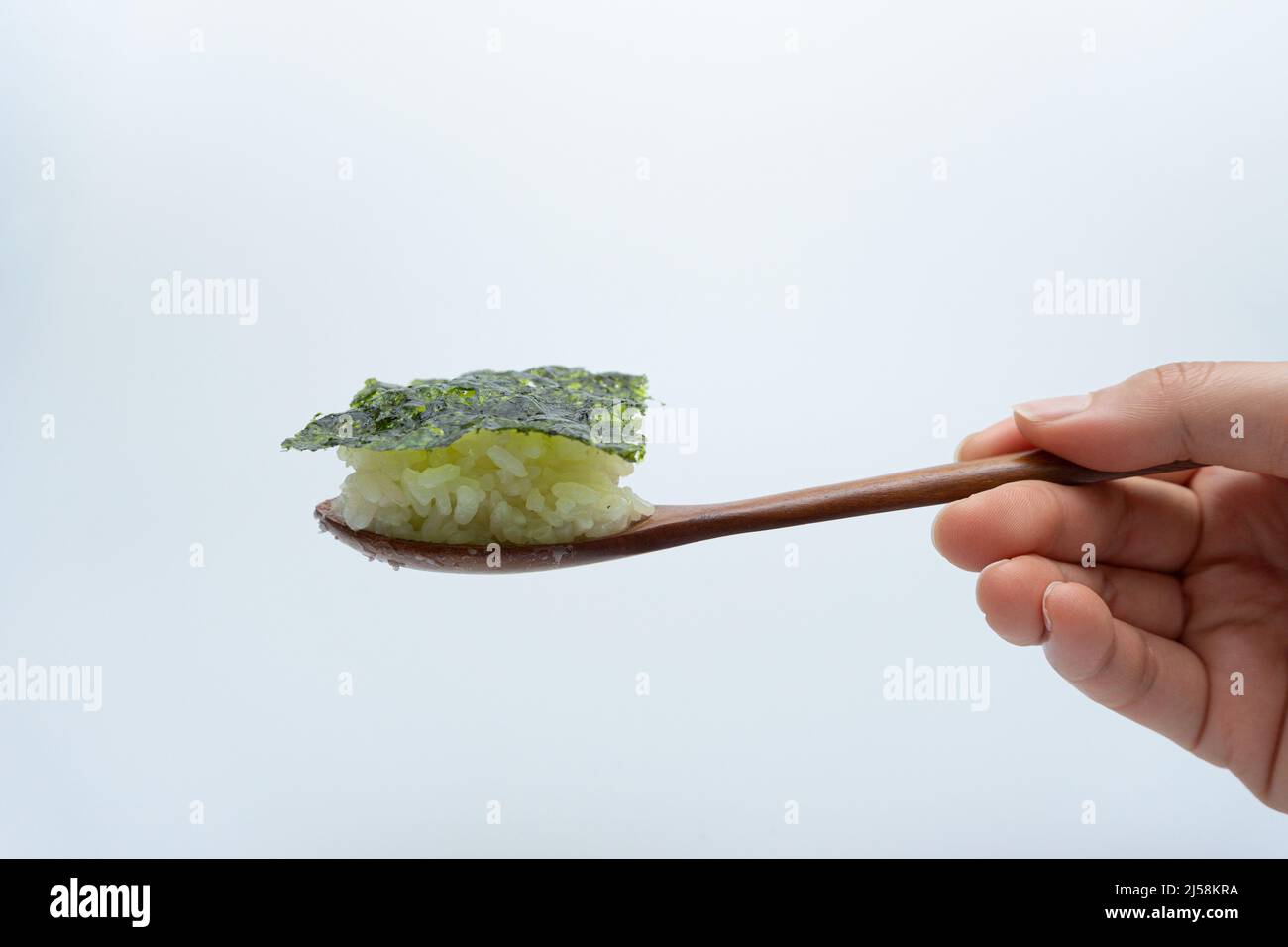 White rice and seaweed on a spoon on a white background Stock Photo - Alamy