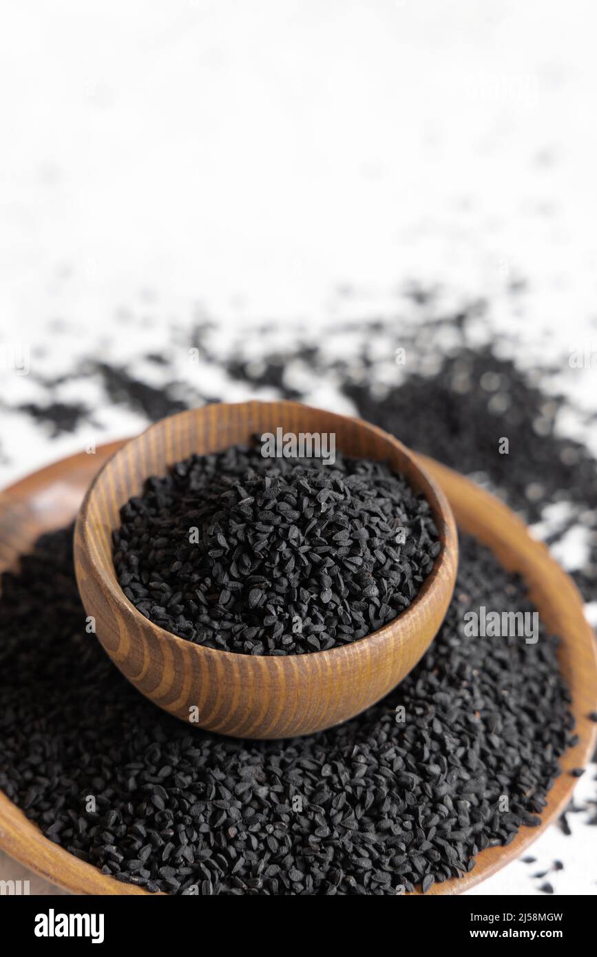 Indian spice Black cumin (nigella sativa or kalonji) seeds in wooden bowls close up with copy space. Traditional medicine, healthy and vegetarian food Stock Photo