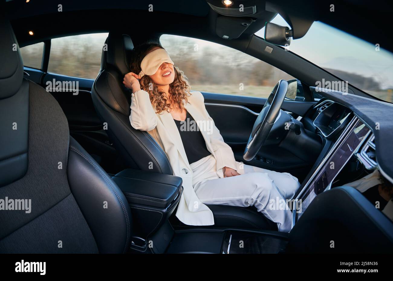 Business woman resting on driver's seat in automobile with bandage for sleep while her car moving on full autopilot. Modern opportunity to rest while vehicle driving independently. Stock Photo