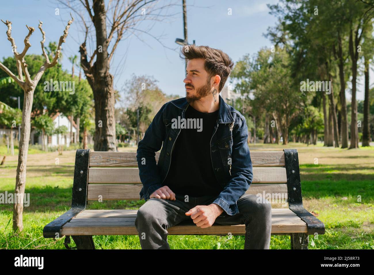 Young man looking thoughtfully ahead, the man waiting for his friend while sitting is wondering what is going on ahead, thoughtful anticipation Stock Photo