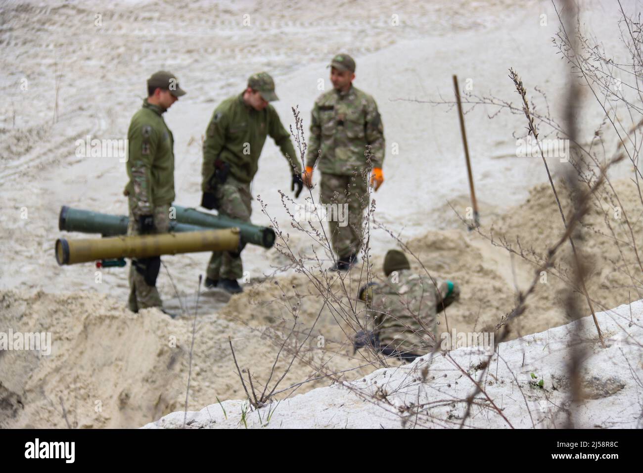 KYIV REGION, UKRAINE - APRIL 20, 2022 - Servicemen arrange the shells in a trench as they work to dispose of ammunition collected in the territories l Stock Photo