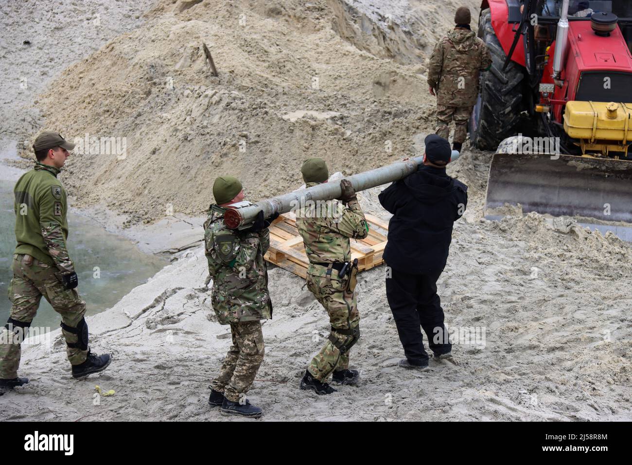 KYIV REGION, UKRAINE - APRIL 20, 2022 - Servicemen carry a shell as they work to dispose of ammunition collected in the territories liberated from Rus Stock Photo