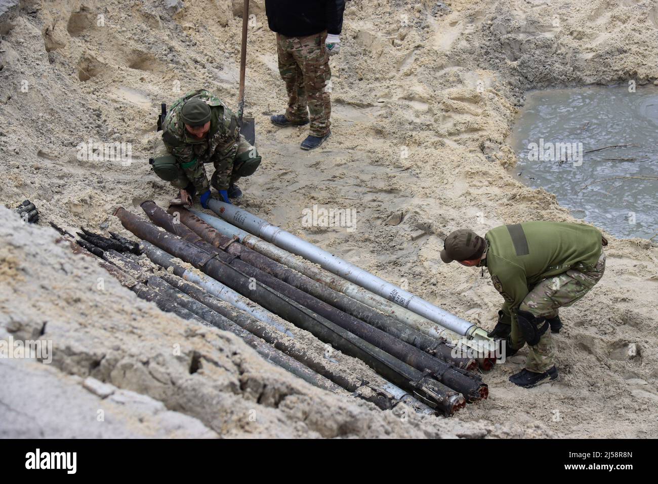 KYIV REGION, UKRAINE - APRIL 20, 2022 - Servicemen arrange the shells on the ground as they work to dispose of ammunition collected in the territories Stock Photo