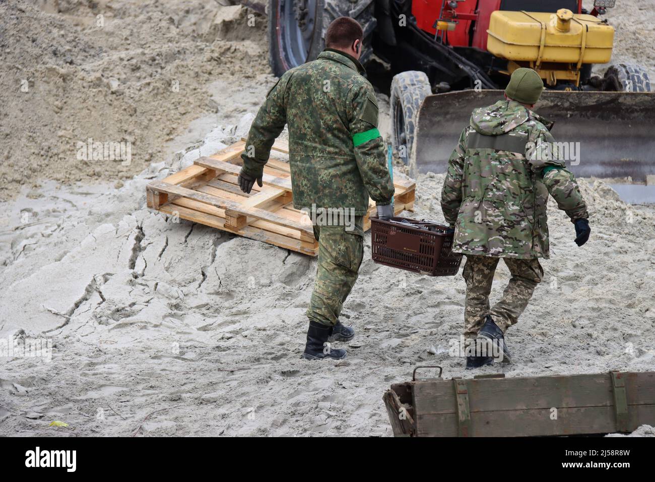 KYIV REGION, UKRAINE - APRIL 20, 2022 - Servicemen carry a crate as they work to dispose of ammunition collected in the territories liberated from Rus Stock Photo