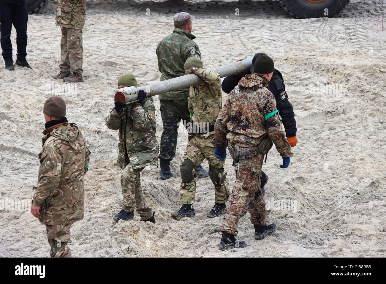 KYIV REGION, UKRAINE - APRIL 20, 2022 - Servicemen carry a shell as they work to dispose of ammunition collected in the territories liberated from Rus Stock Photo