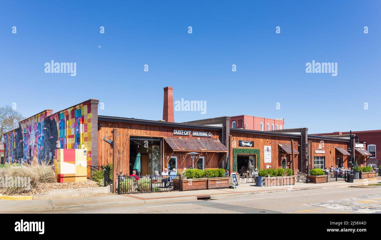 ROCK HILL, SC, USA-10 APRIL 2022: Specialty shops in downtown with outside sidewalk sitting and dining. Sunny spring day, people. Mural on end wall. Stock Photo