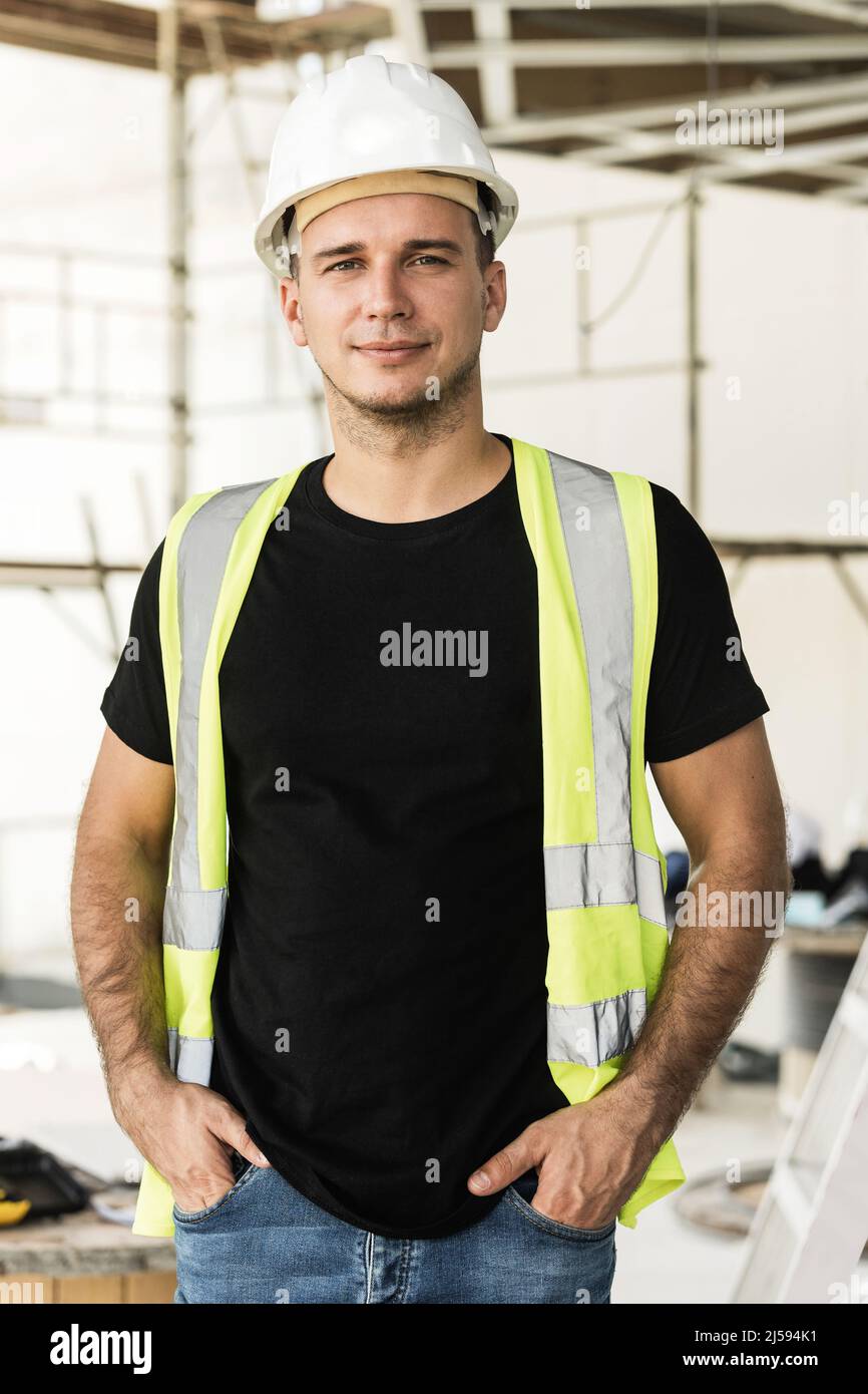 Young worker wearing hard hat nad safety vest on a construction site