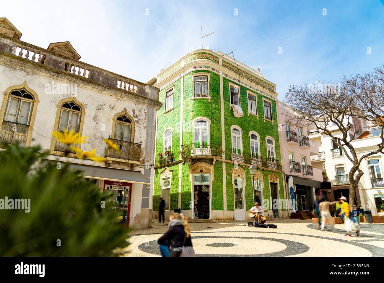 Historical town centre in Lagos, Algarve, Portugal with moving people and a building with green ceramic tiles. Stock Photo
