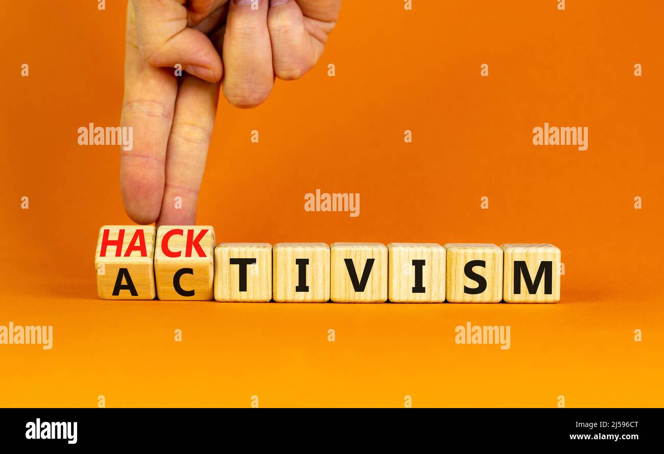 Activism or hacktivism symbol. Businessman turns wooden cubes and changes the word Activism to Hacktivism. Beautiful orange table orange background, c Stock Photo