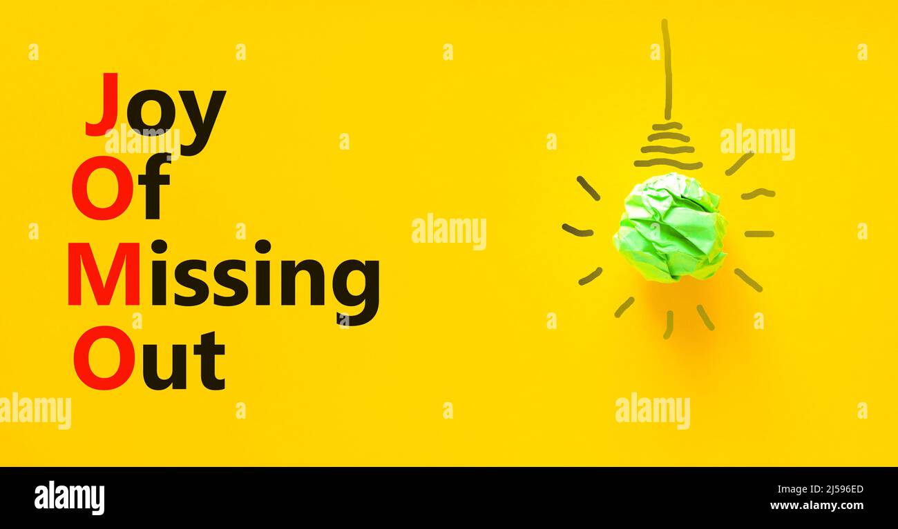 JOMO joy of missing out symbol. Concept words JOMO joy of missing out on beautiful yellow background. Green light bulb icon. Light bulb icon. Business Stock Photo