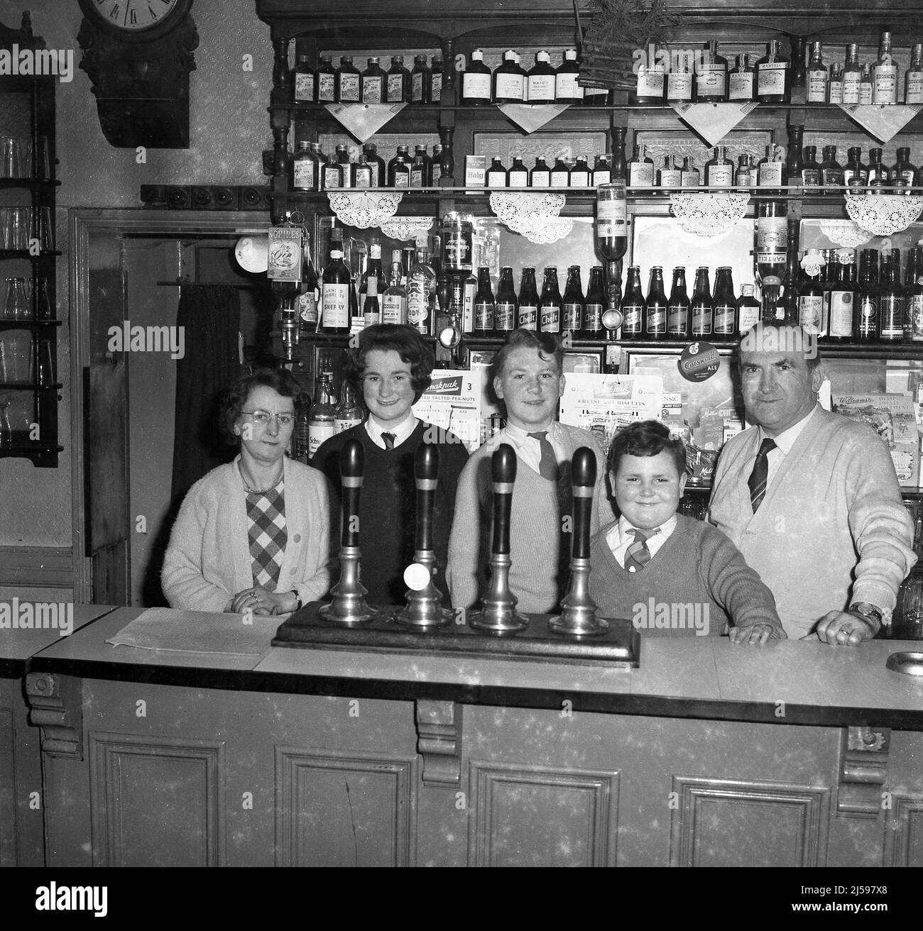 1962, historical, three schoolchildren standing behind the bar with their grandparents, the landlord and landlady of the Padding Pub, Cheltenham, Gloucester, England, UK. Stock Photo