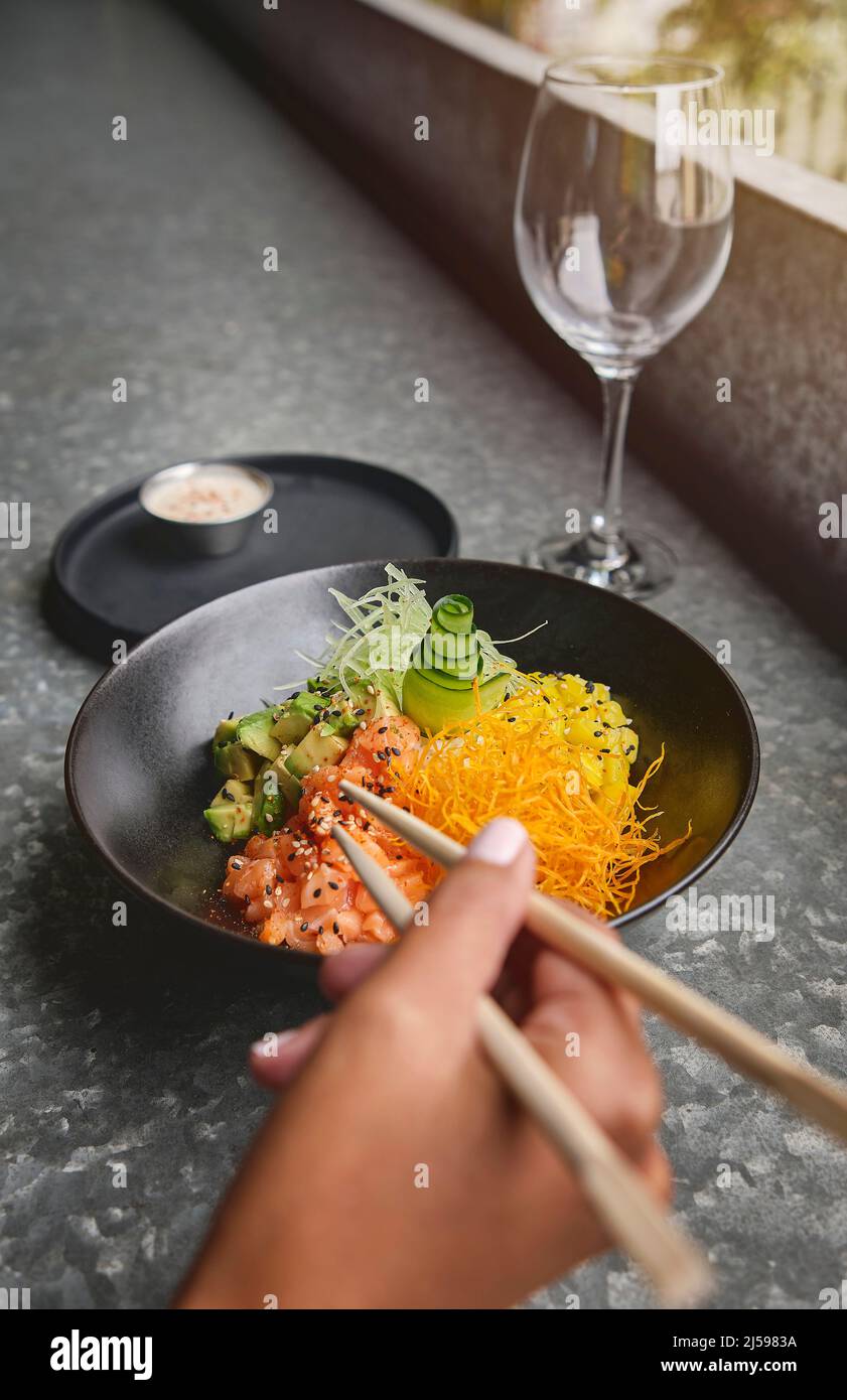 Woman eating traditional Hawaiian dish poke bowl with fork. Diet and